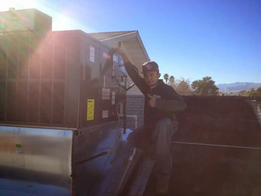HVAC technician performing HVAC Inspection on a rooftop unit in Harvard